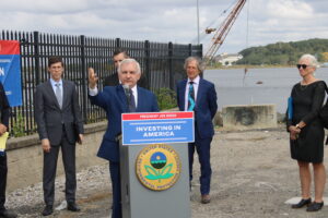 Senator Jack Reed at a Podium in front of a Harbor. 